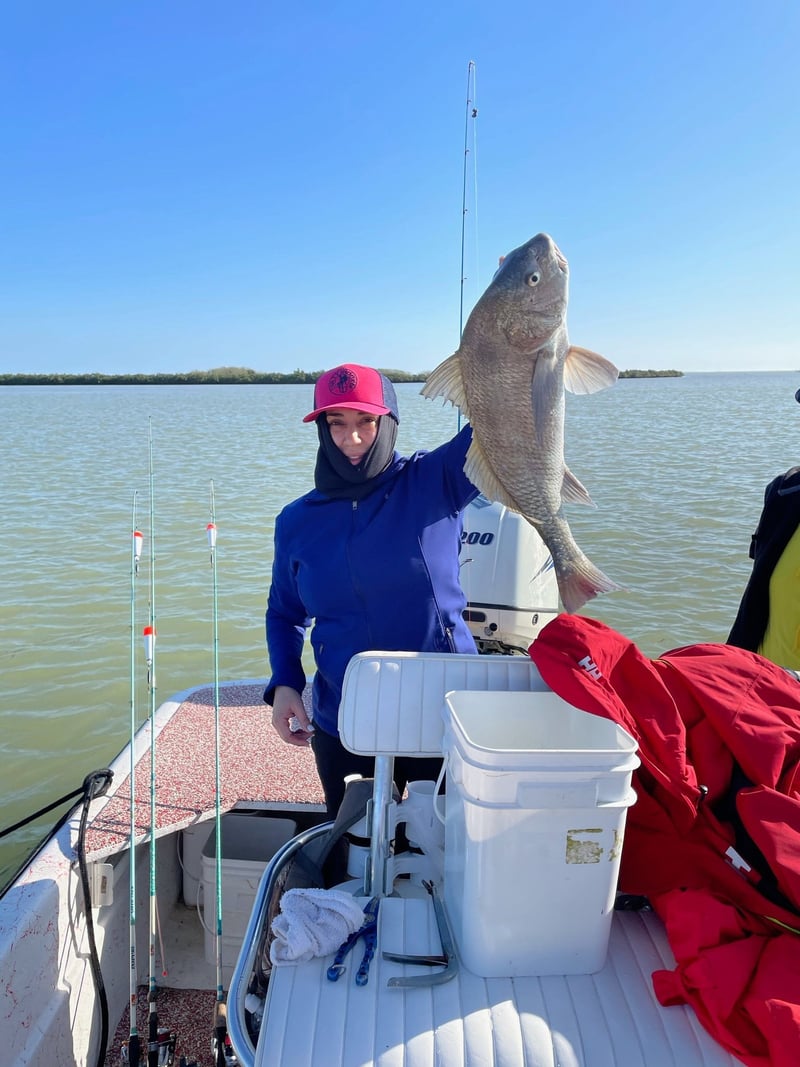 A woman is holding a large fish on a boat.