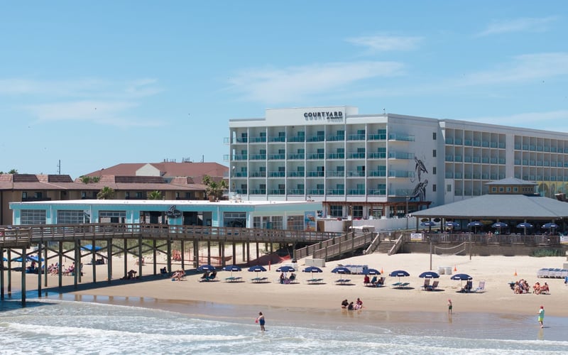 A beach with a pier and a large building in the background
