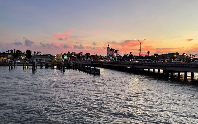 A sunset over a body of water with a lighthouse in the distance.