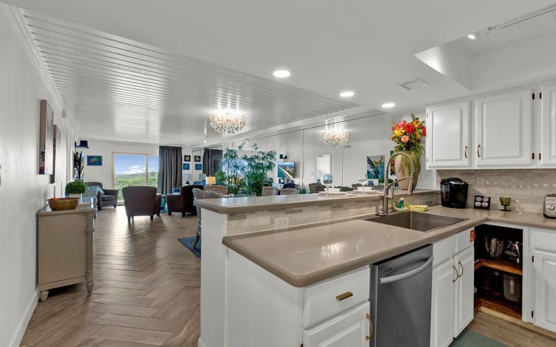 A kitchen with white cabinets , a sink , and a dishwasher.