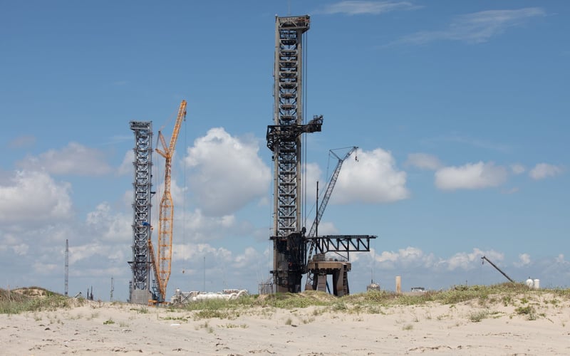 A large crane is sitting in the middle of a sandy field.