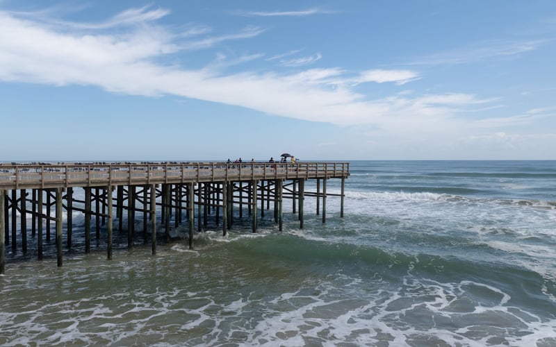 A pier leading into the ocean on a sunny day.