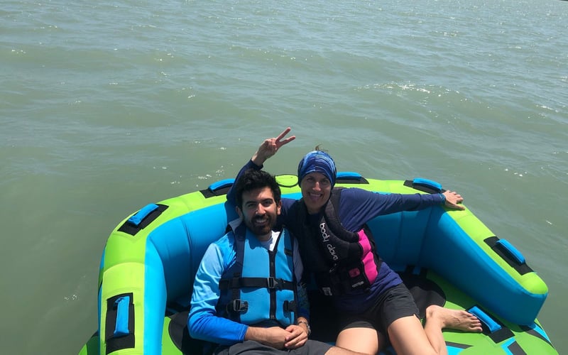 A man and a woman are sitting on an inflatable boat in the water.