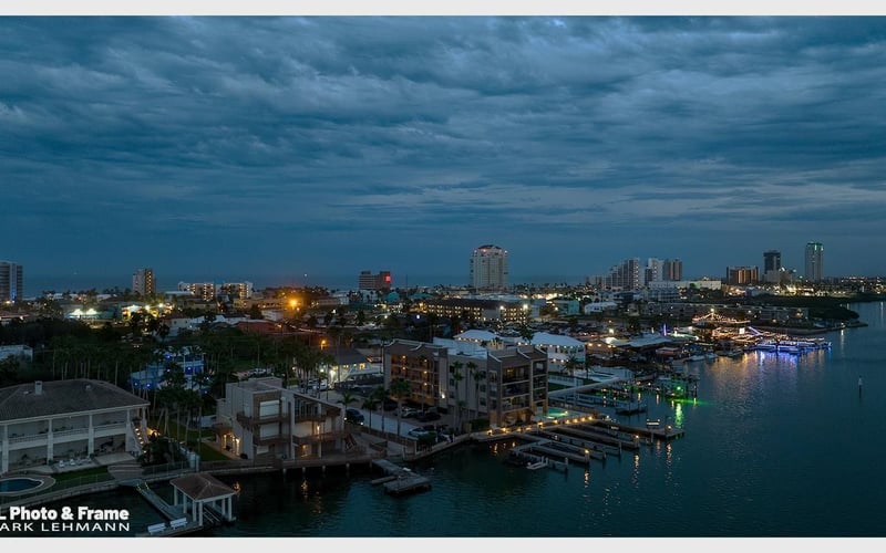 An aerial view of a city at night with a body of water in the foreground.