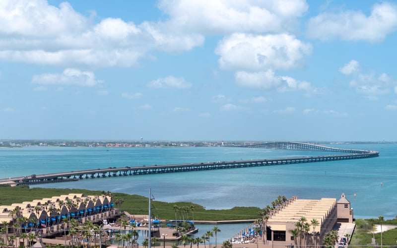 An aerial view of a large body of water with a bridge in the distance.