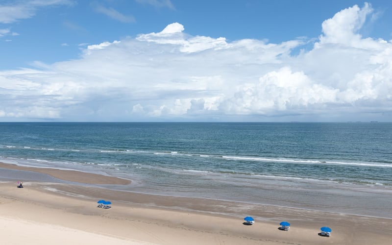 A beach with blue chairs and umbrellas on a sunny day.