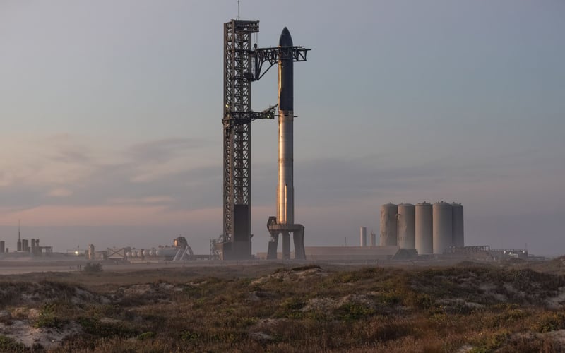 A large rocket is sitting on top of a dirt field.