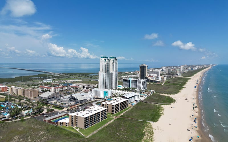 An aerial view of a beach with a city in the background.