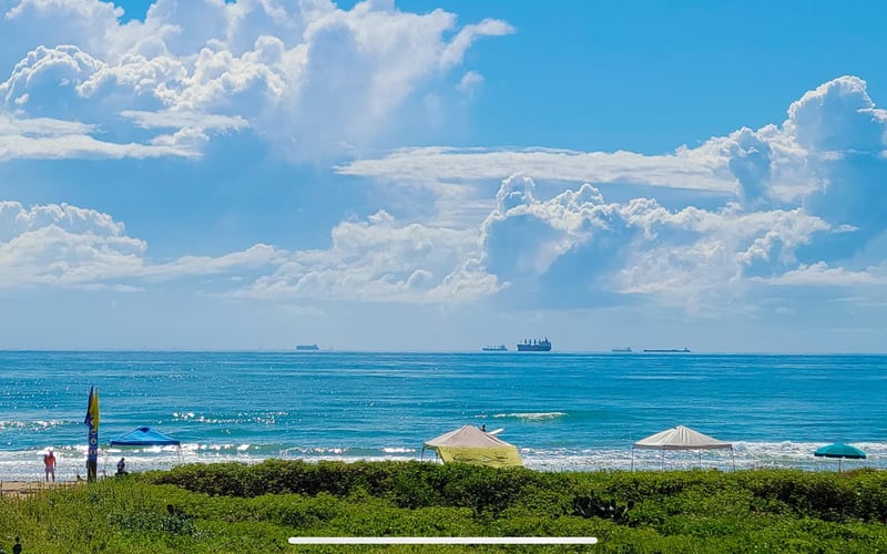 A view of the ocean from a beach on a sunny day.