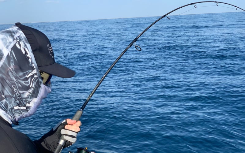 A man is fishing in the ocean with a fishing rod.