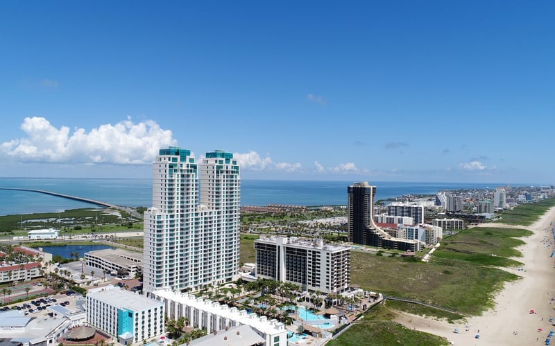 An aerial view of a beach with a lot of buildings in the background.