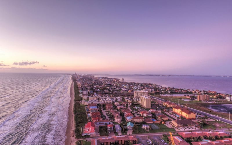 An aerial view of a city next to the ocean at sunset.