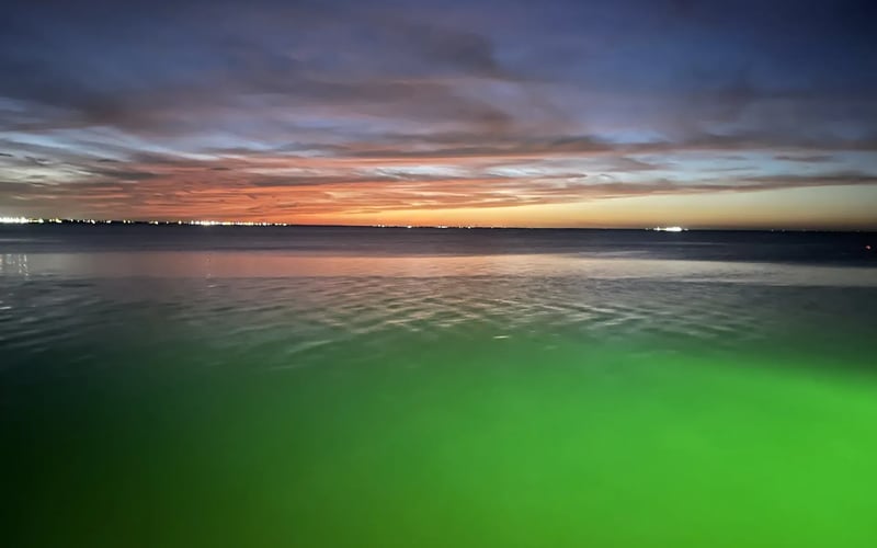 A sunset over a body of water with a green background.