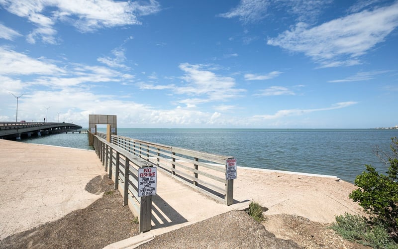 A wooden pier leading to the ocean on a sunny day.