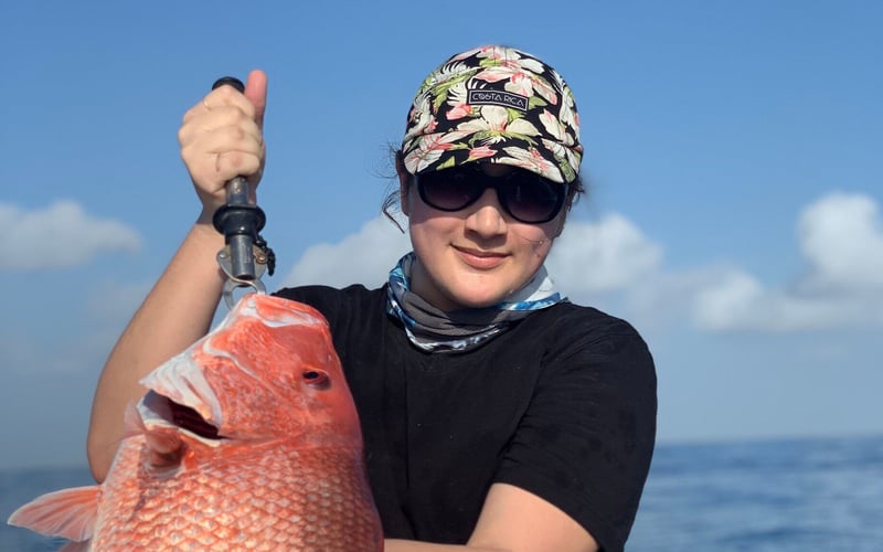 A woman is holding a large red fish in her hands.